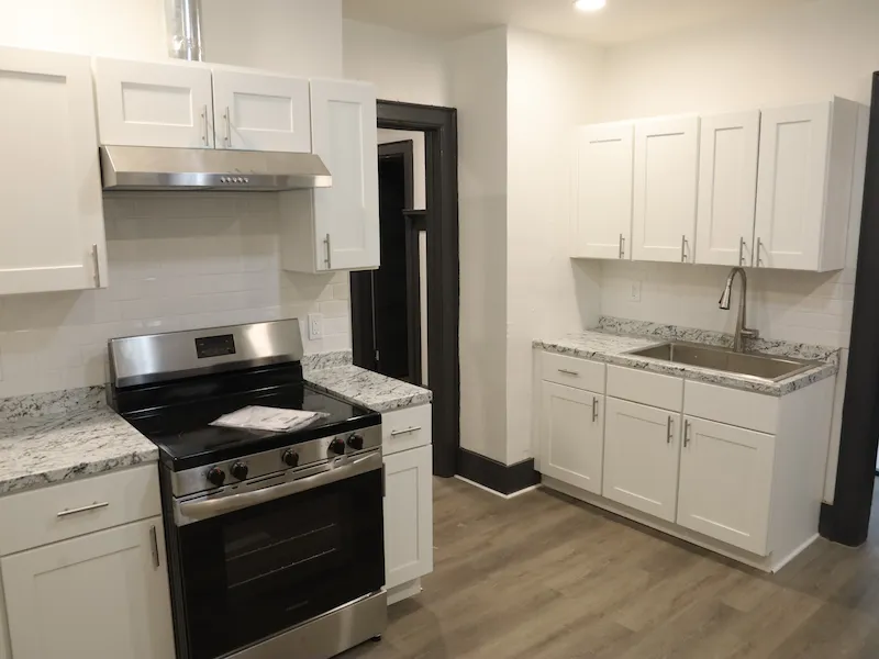 Updated kitchen with white walls and cabinets, marble countertops, and gray trim