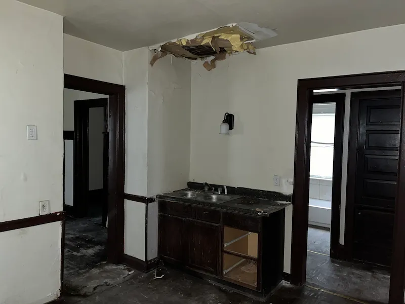 Dark interior room with floor removed. White walls and dark wood trim