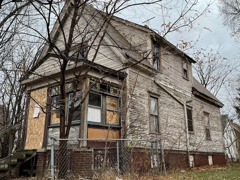 Old boarded up house with damaged siding