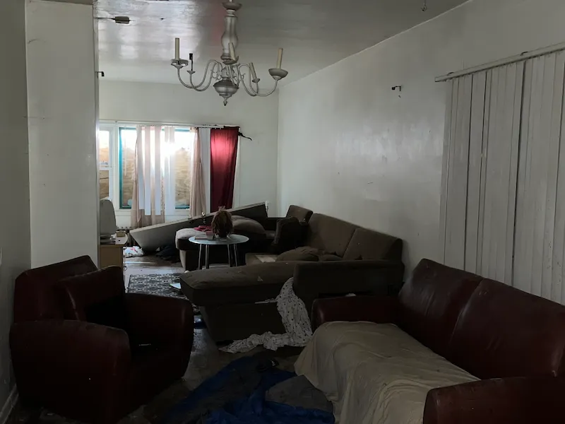 Messy interior room with white walls, full of old furniture