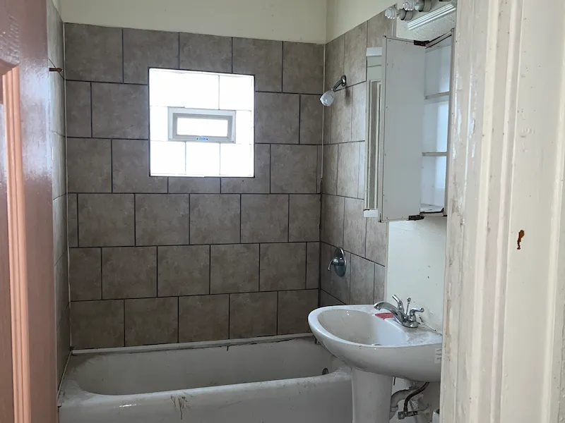 Old bathroom with dirty tub and old gray tiled wall