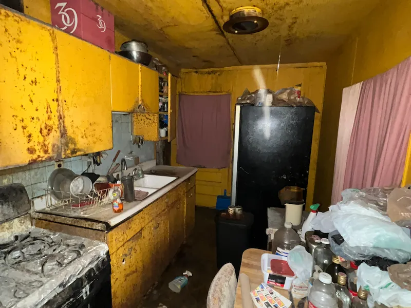 Old kitchen with yellow walls and filled with trash